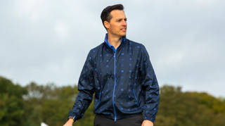 A golfer poses in the Original Penguin Logo Print Golf Wind Jacket