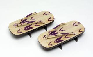 A pair of Japanese wooden shoes with purple markings on them.