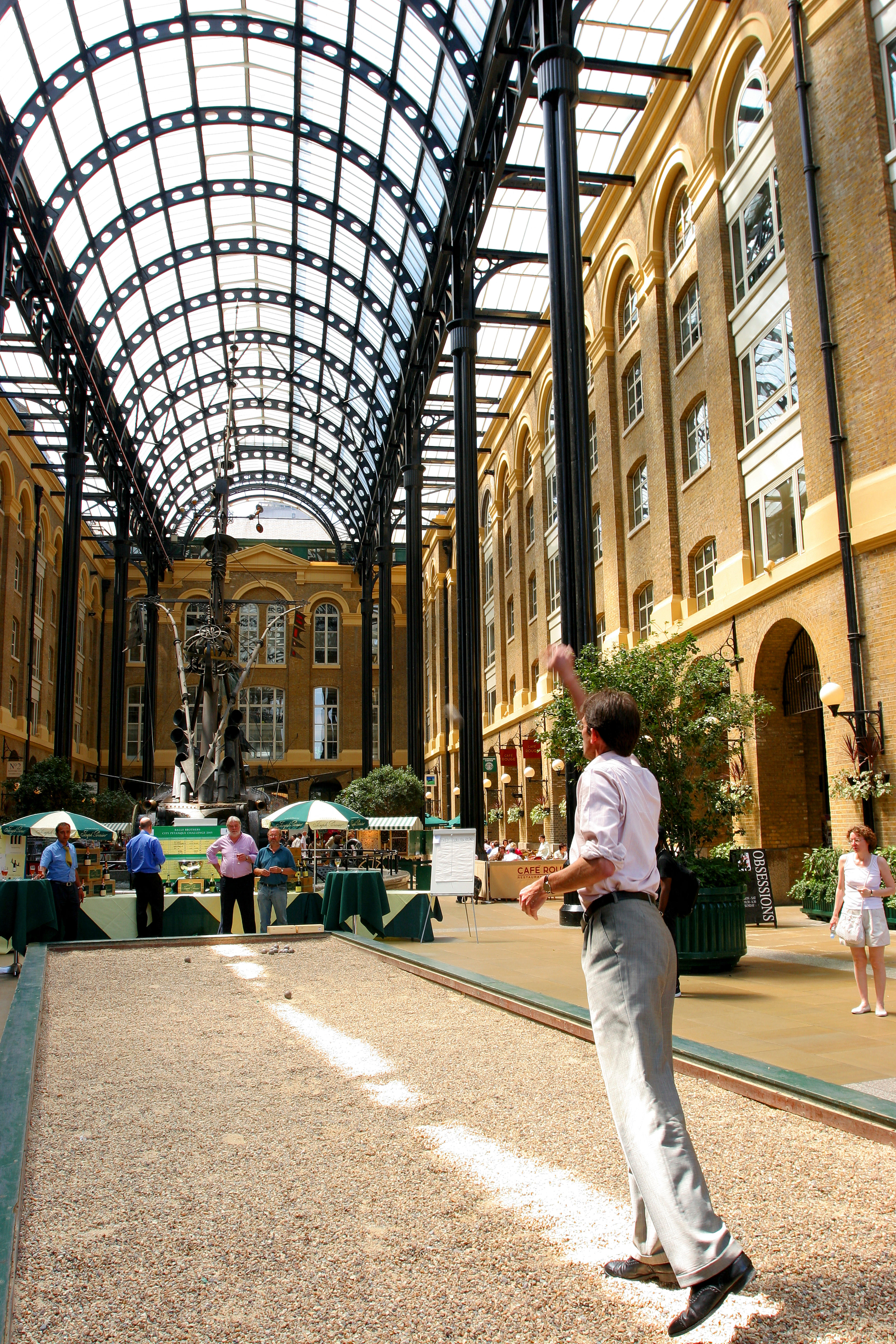 A man in a suit plays petanque inside Hay's Galleria in London
