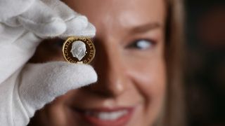 An assistant holds up the new £1 coin design, showing Charles's face in profile