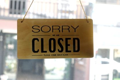 Text written Sorry we're closed hang on mirror door at restaurant.