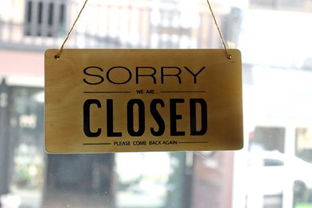 Text written Sorry we're closed hang on mirror door at restaurant.