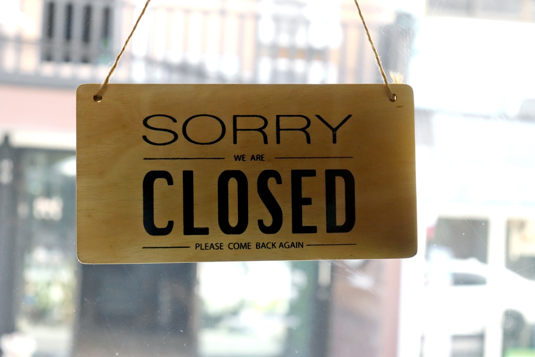 Text written Sorry we're closed hang on mirror door at restaurant.