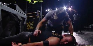 Shawn Michaels tending to Adam Cole after being punted by Pat McAfee
