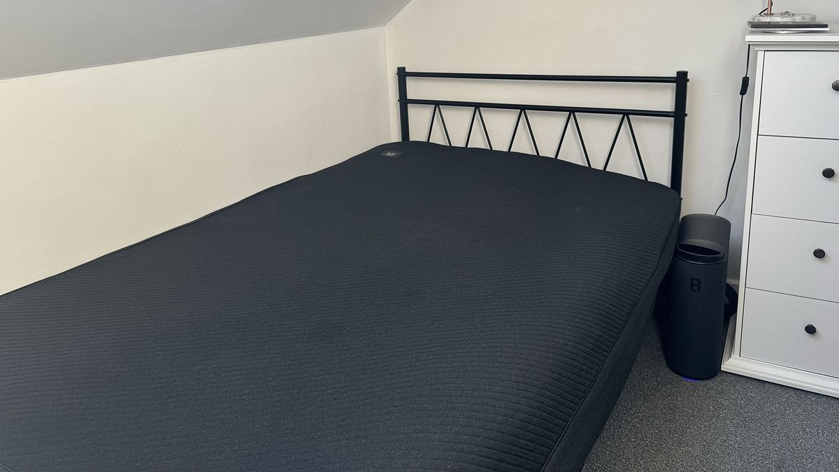 The Eight Sleep Pod 4 mattress cover on a bed in our reviewer's bedroom, with the control tower next to the bed