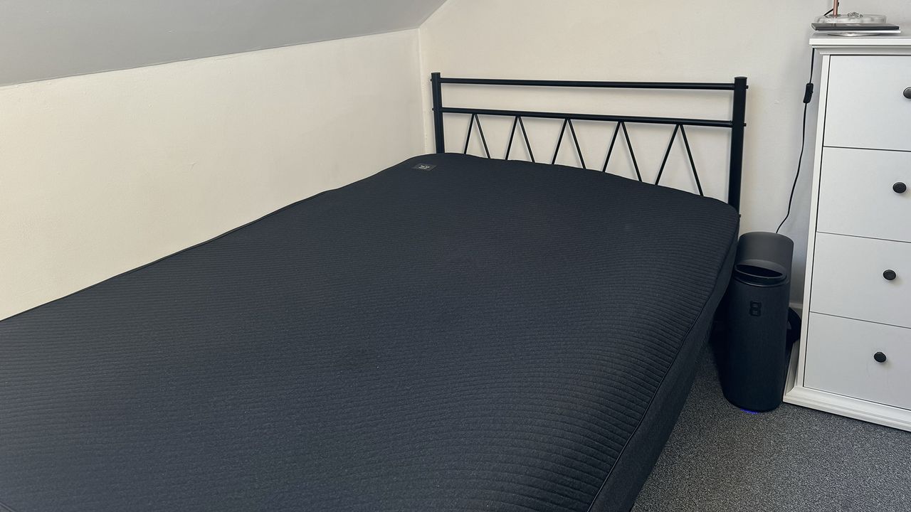 The Eight Sleep Pod 4 mattress cover on a bed in our reviewer's bedroom, with the control tower next to the bed