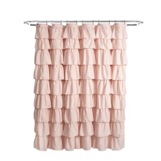 A light pink ruffled shower curtain hanging on a curved silver rod