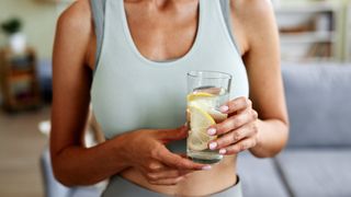 a photo of a woman wearing gym kit holding lemon water