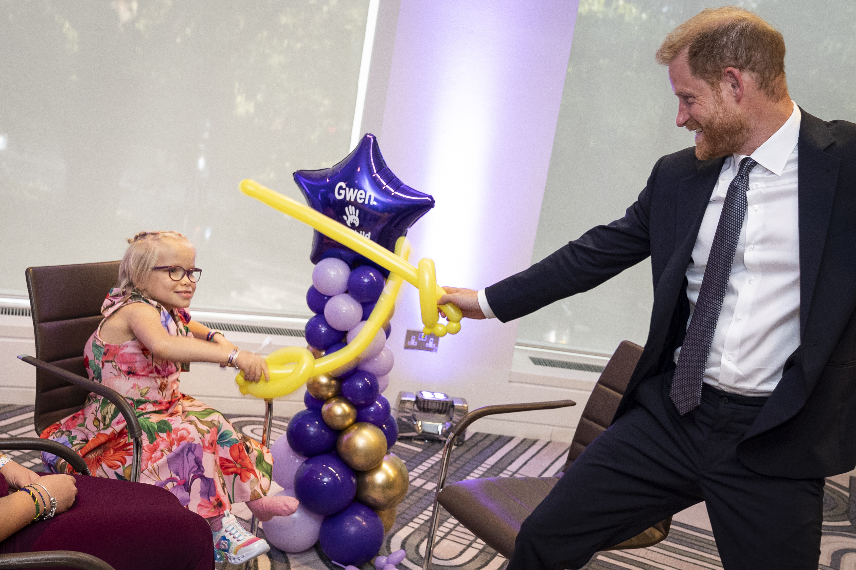 Prince Harry playing with a balloon sword with a little girl