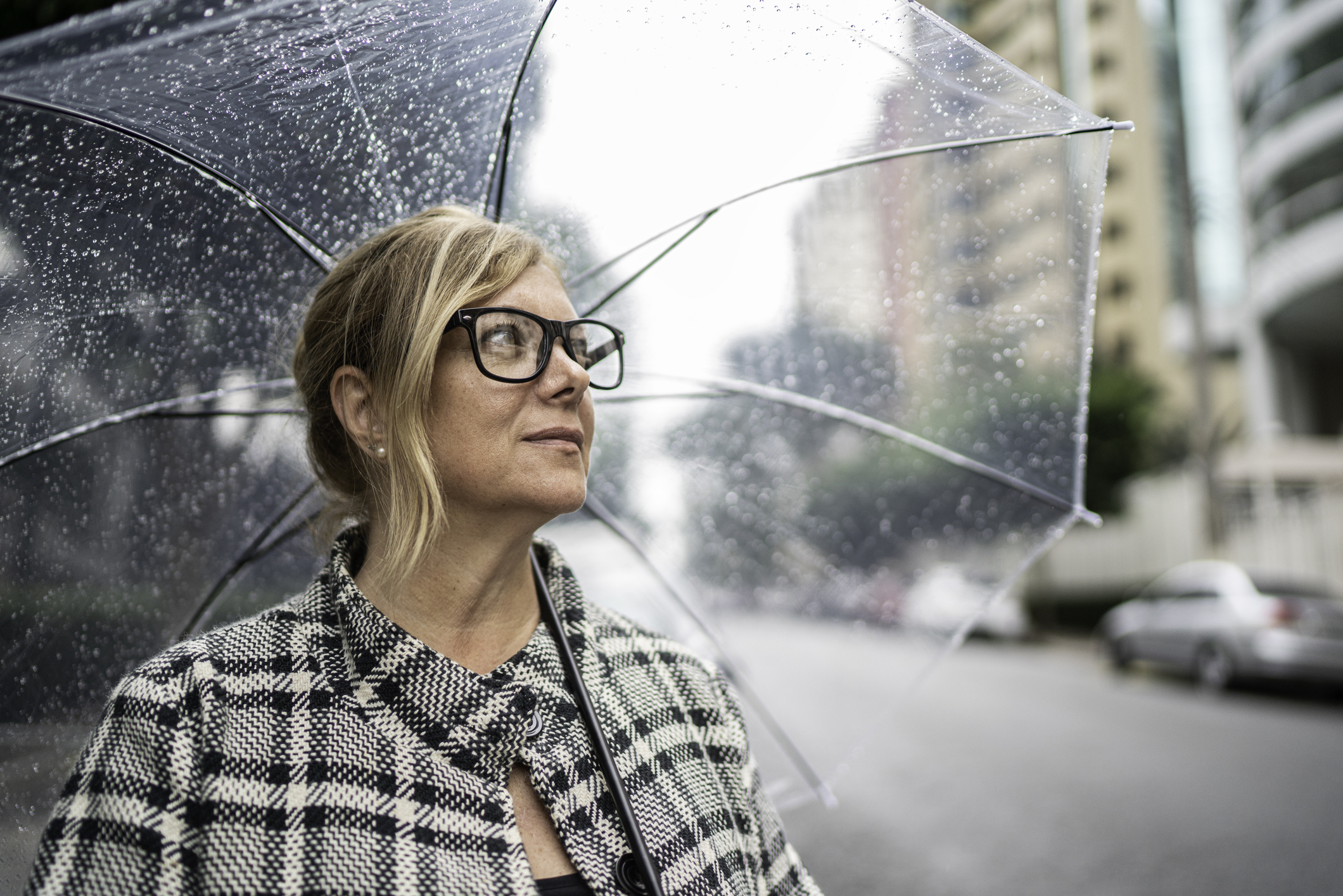 Mature woman looking away using umbrella outdoors