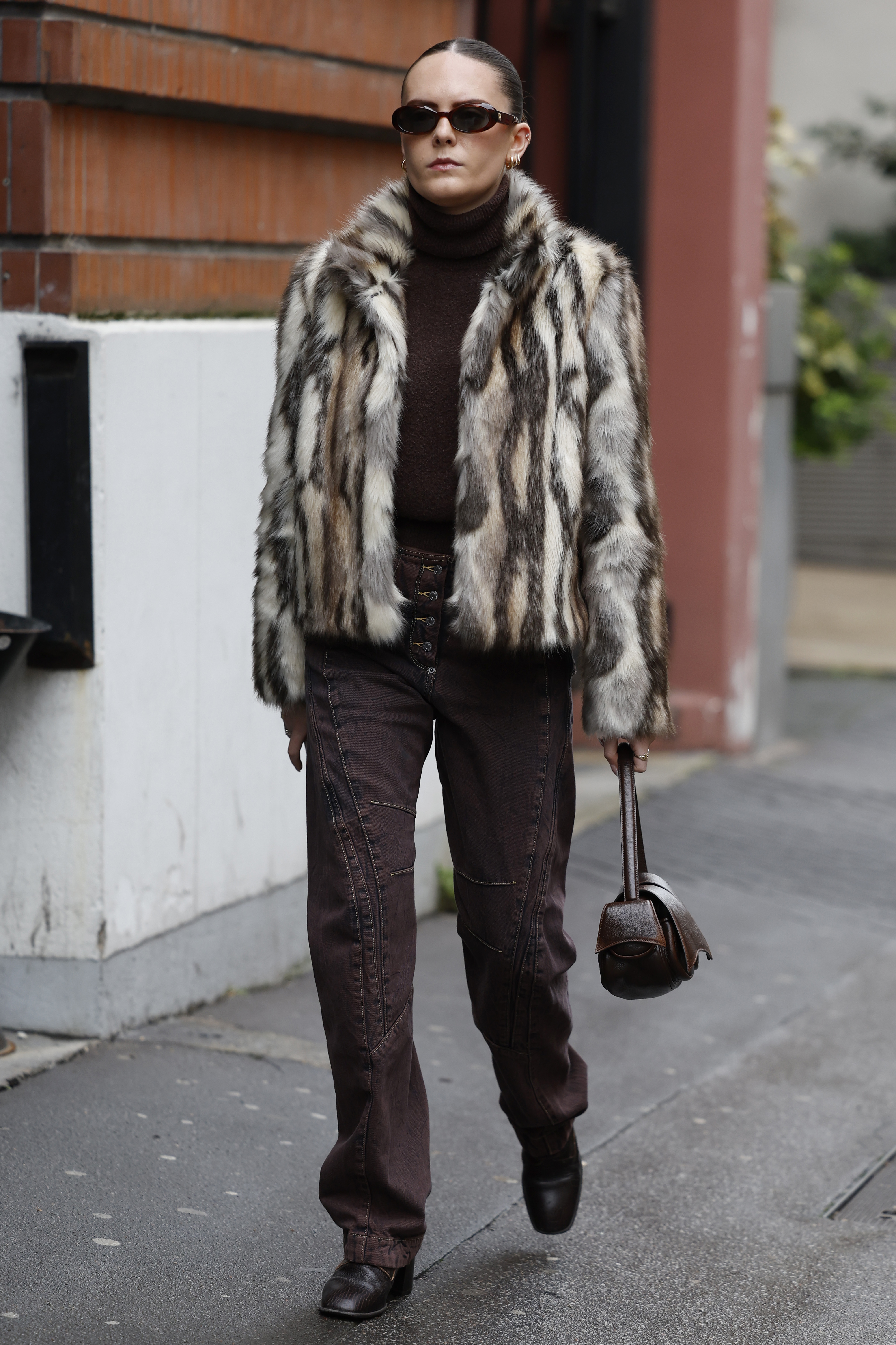 PARIS, FRANCE - JANUARY 25: A guest wears brown turtleneck sweater, brown jeans, beige and brown fur jacket, brown bag, outside Kiko Kostadinov, during the Menswear Fall Winter 2025/2026 as part of  Paris Fashion Week on January 25, 2025 in Paris, France. (Photo by Claudio Lavenia/Getty Images)