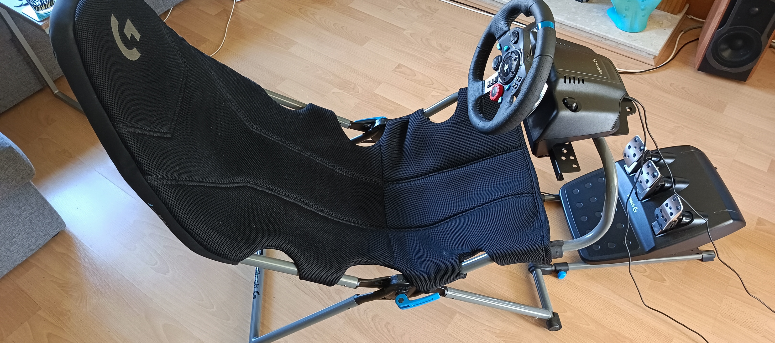 A black and grey Playseat Challenge X Logitech G Edition sim racing chair sitting in a wood-floored lounge