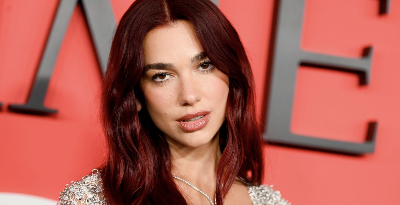 dua lipa walks the red carpet red carpet wearing a silver dress