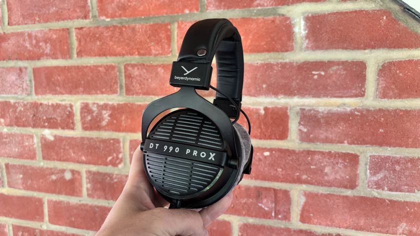 Beyerdynamic DT 990 Pro X headphones held up against brick wall