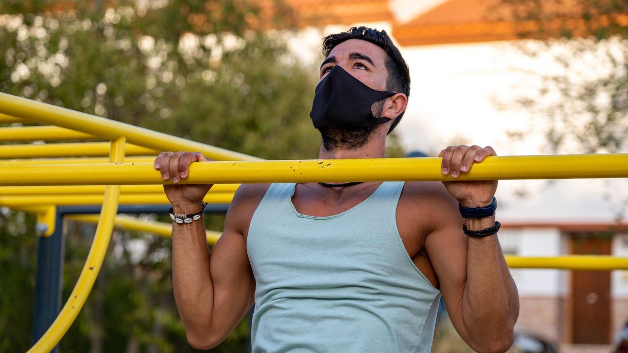 Man doing a pull up wearing a protective face mask