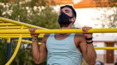 Man doing a pull up wearing a protective face mask