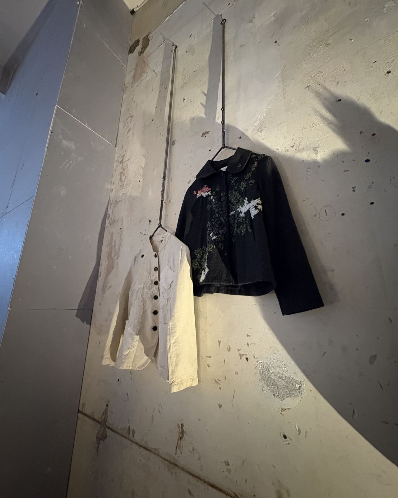 Installation view of a fashion and design exhibition featuring clothes, homeware, retro-looking tvs showcasing audiovisual works, large posters, and more.