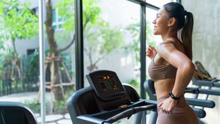 Woman running on a machine in the gym wearing workout clothes