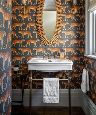 Leopard wallpaper and a white sink in a box room turned powder room.