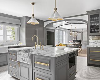 A kitchen lighting idea with coned chandelier fitting over grey island with marble counter