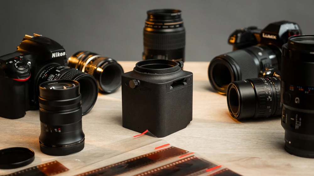 Valoi Easy35 surrounded by digital cameras and lenses on a wooden surface
