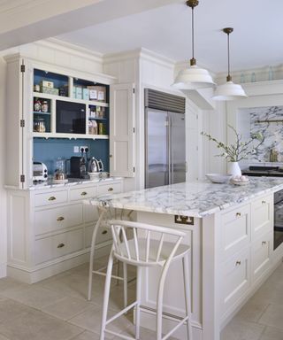 Pantry cabinet with doors open in front of kitchen island in white kitchen