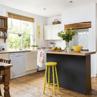 kitchen with white wall wooden counter yellow stool and window