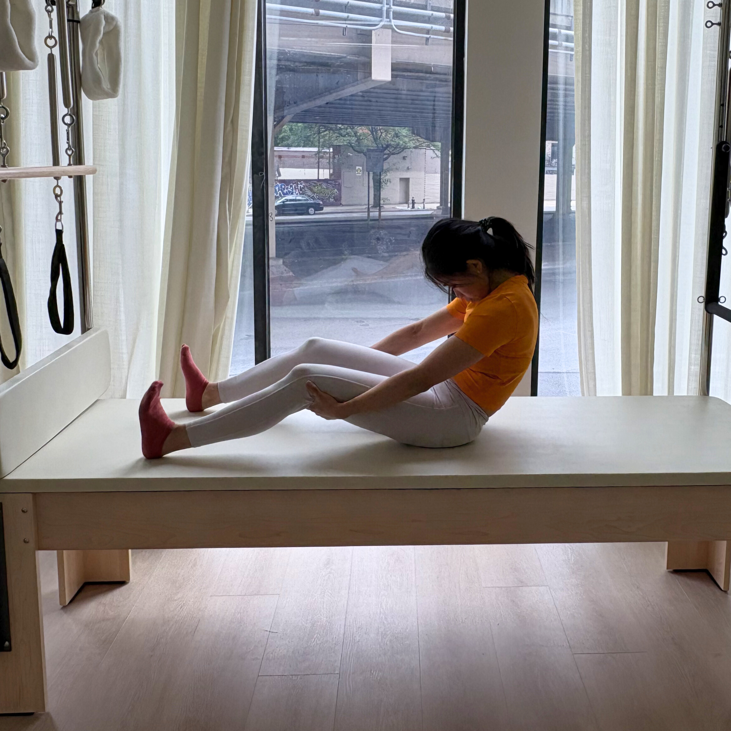 Woman demonstrates exercise on reformer bed