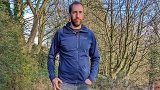 Man wearing Rab Superflux Hoody fleece top in woods