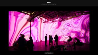 A screen capture of interactive artist Marpi's website, featuring his installation melting room in which pink colours swirl across the walls of a gallery space.