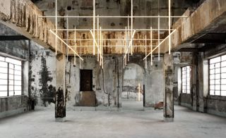 Illuminated tubes hang in a grid-like system inside an industrial space