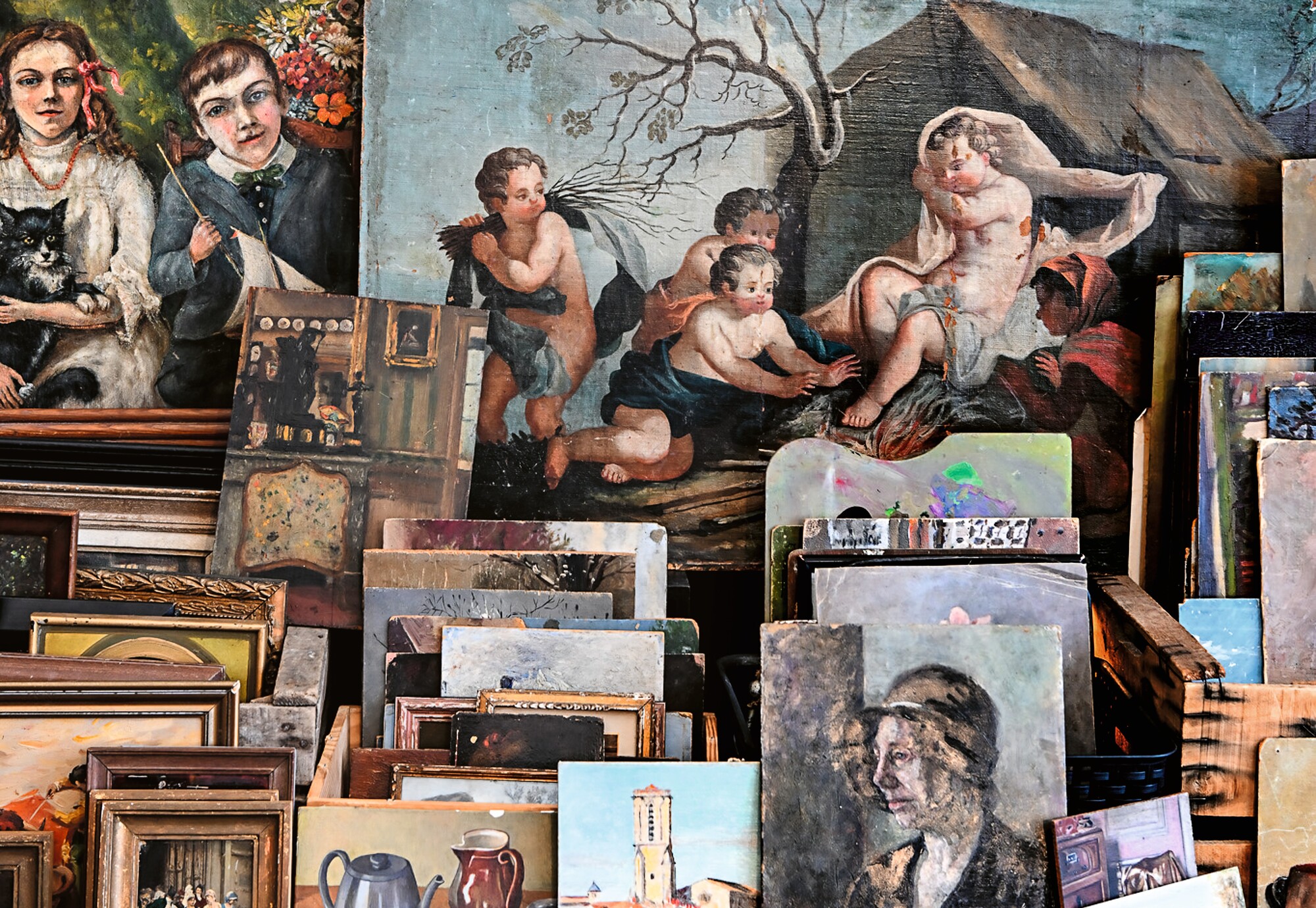 a pile of antique artworks in and out of frames stacked up on the side of the road