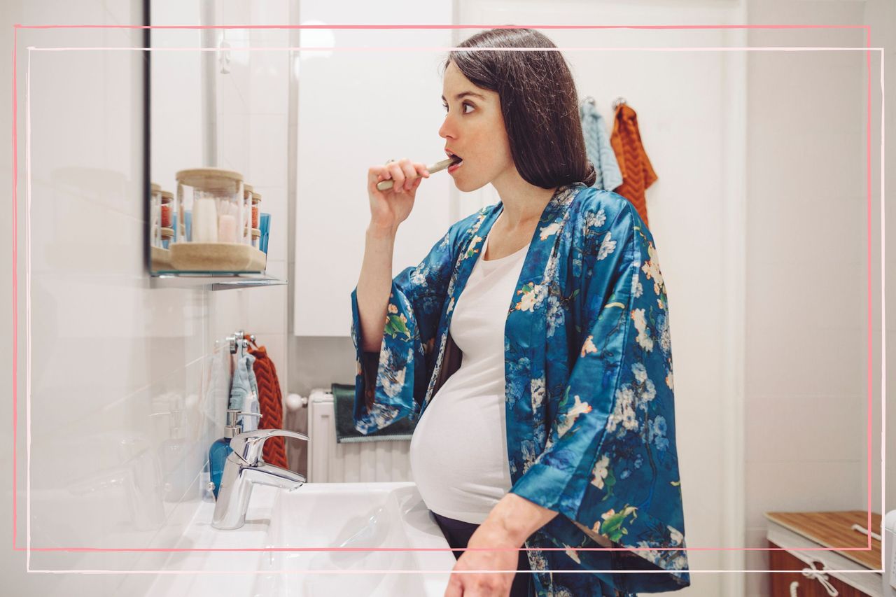 A pregnant woman brushes her teeth wearing a turquoise kimono