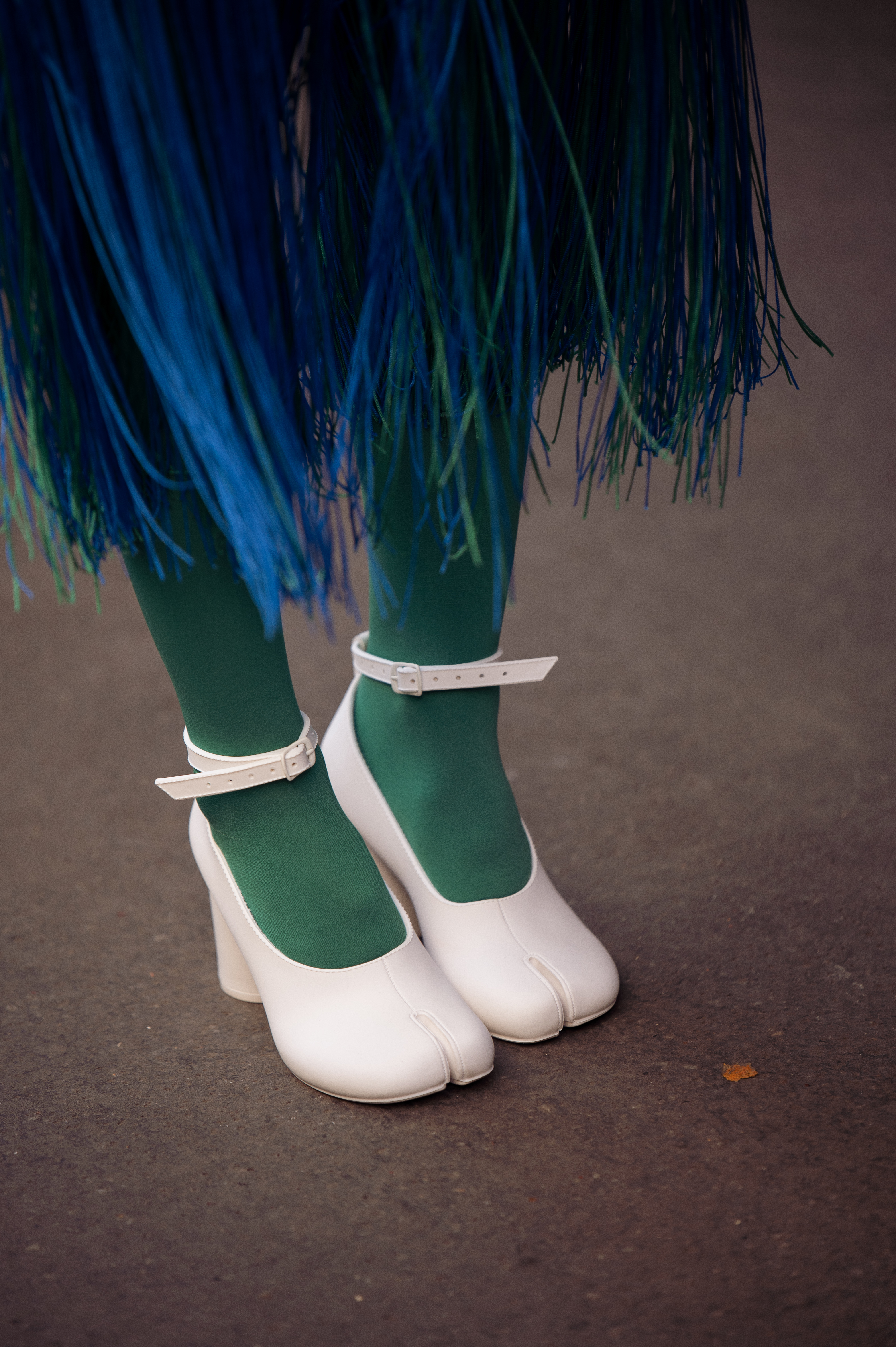 PARIS, FRANCE - FEBRUARY 28: A guest is seen wearing a blue checked coat with fringed details or tassels on the bottom part, green tights, white shoes with split toes and white bag, outside Victoria/Tomas, during Paris Fashion Week - Womenswear Fall Winter 2023 2024, on February 28, 2023 in Paris, France. (Photo by Raimonda Kulikauskiene/Getty Images)