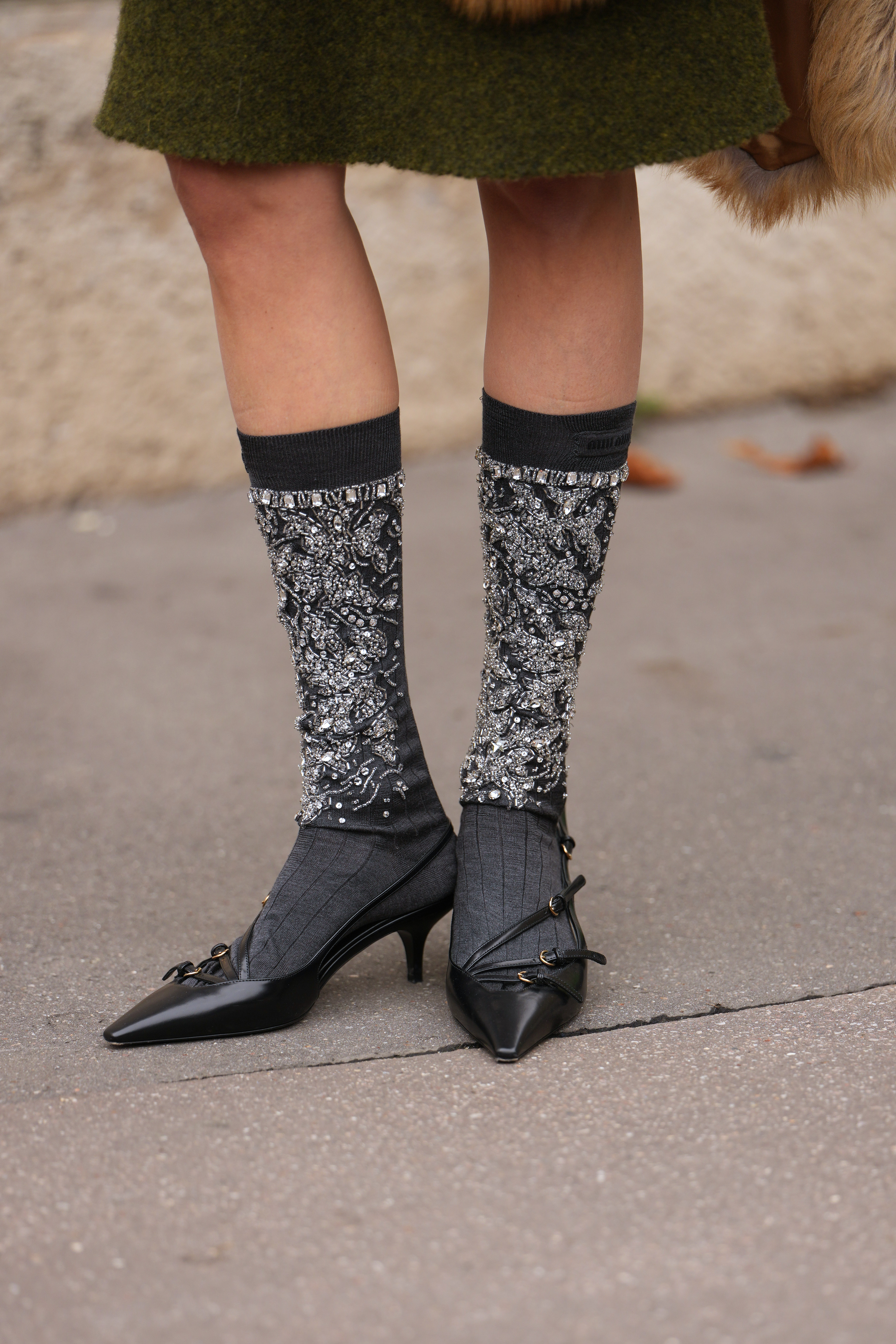 PARIS, FRANCE - OCTOBER 06: Leonie Hanne wears an olive green wool knit knee-length skirt, grey and silver sequin knee socks with black top bands, black leather pointed-toe shoes with a small heel, outside Miu Miu, during Paris Fashion Week - Womenswear Spring Summer 2026, on October 06, 2025 in Paris, France (Photo by Edward Berthelot/Getty Images)