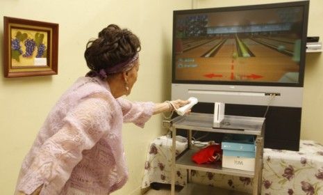 A senior citizen bowls with the Nintendo Wii: The Wii&amp;#039;s once-unique motion-sensor console now faces tough competition from devices like Microsoft&amp;#039;s Xbox Kinect.