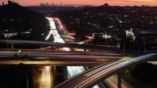 Motorists drive cars and other vehicles during the late afternoon commute with downtown Los Angeles in the distance 