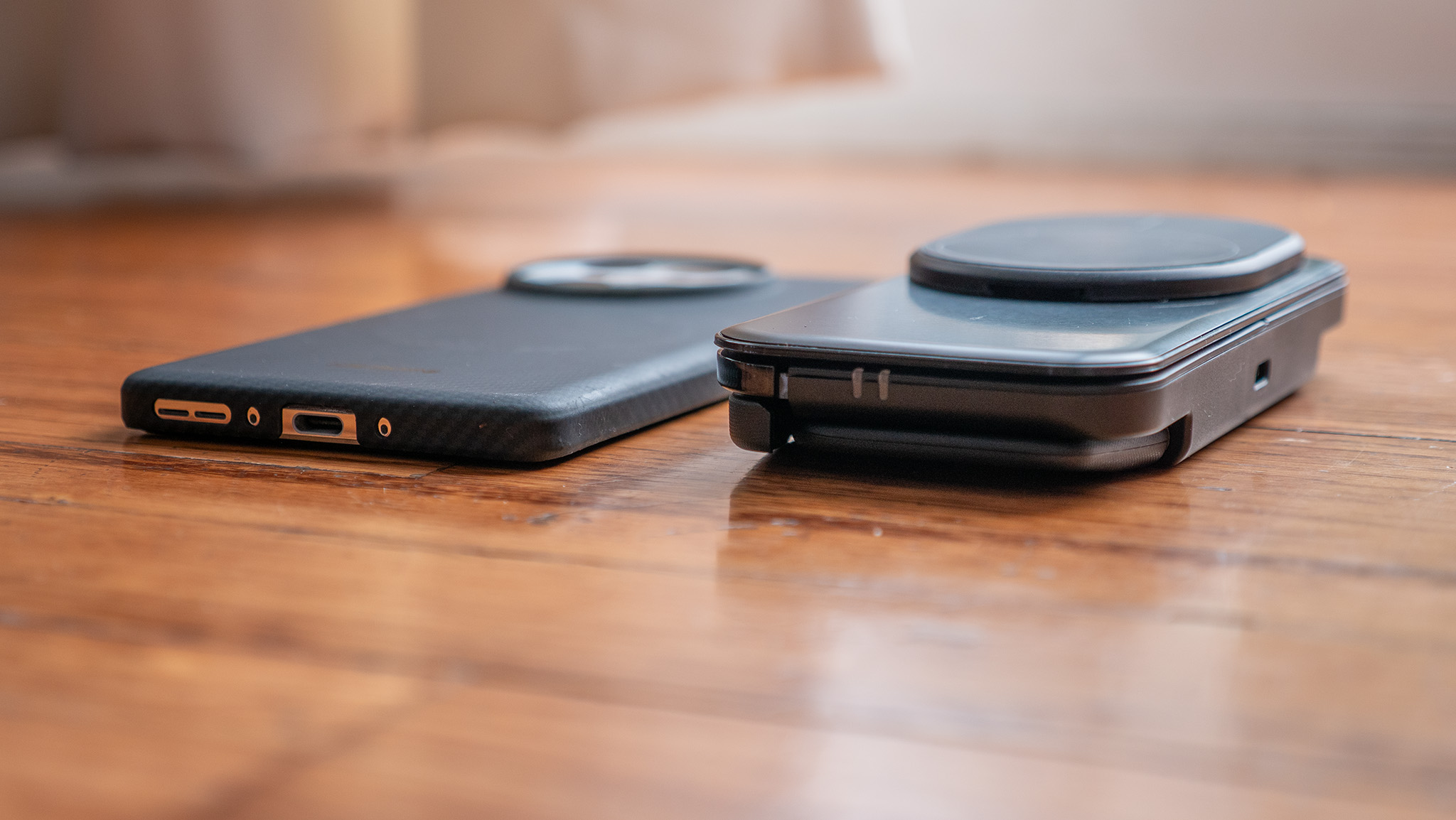 An Ohsnap MCON controller is closed and placed next to a OnePlus 13 wearing a Thinborne case to show its diminutive size