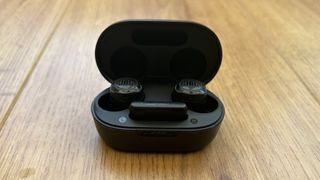 JBL Quantum TWS Air earbuds in case on a wooden surface