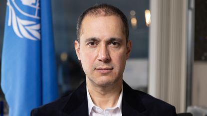 Portrait of Kaveh Madani with a UN flag in the background.