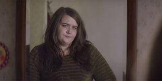 Aidy Bryant leaning against a doorway in a brown sweater on Shrill.