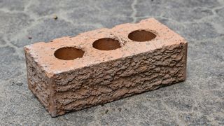 Photo of a reddish brown brick sitting on the ground