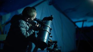 Boy looking through the eyepiece of a telescope at night
