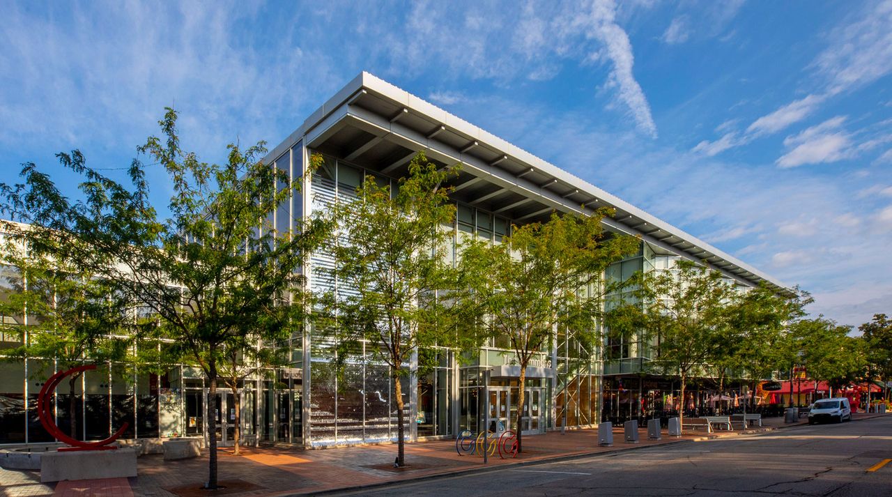 Architectural installation on a street with planted trees on the pavement in front of it.