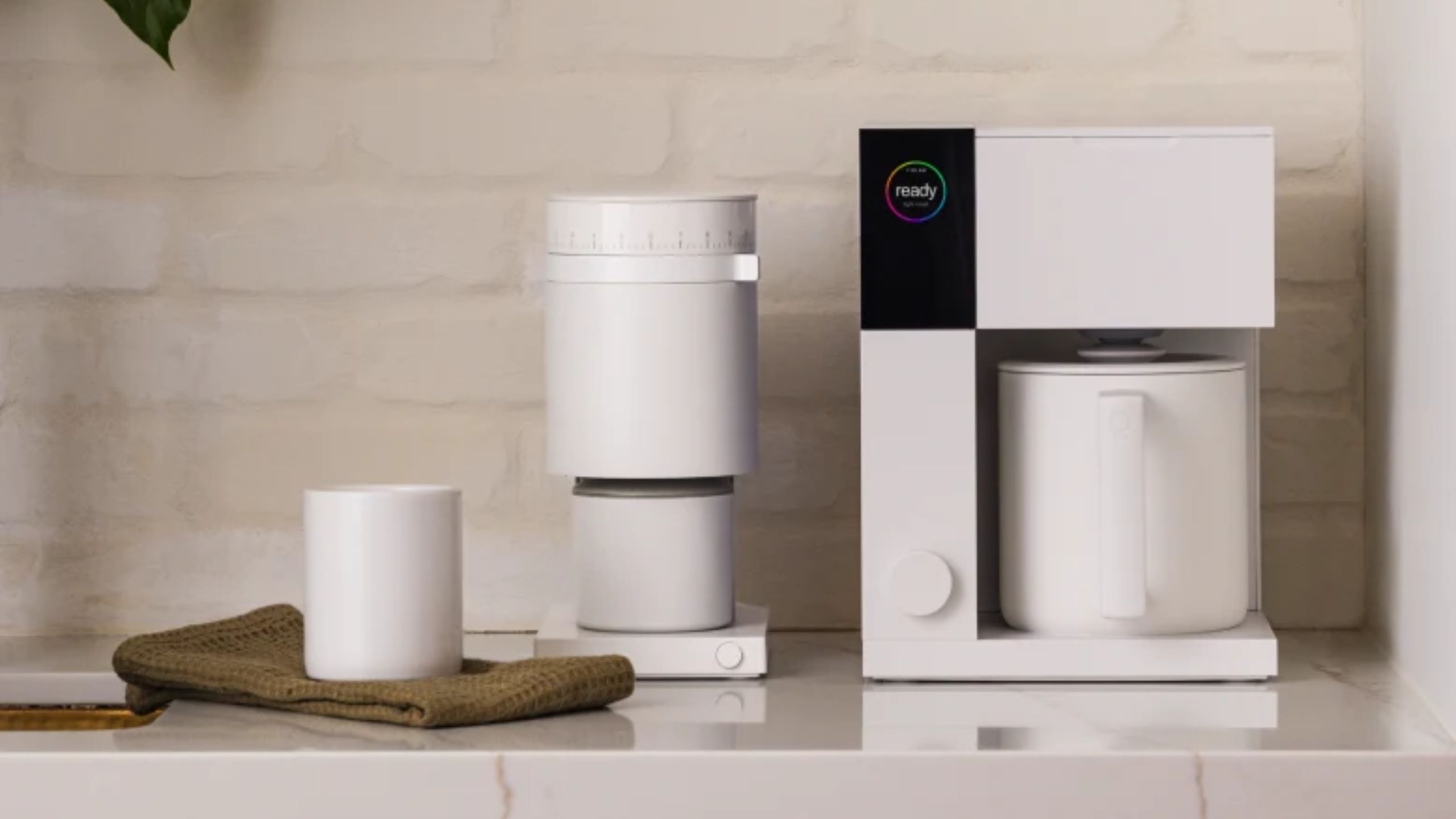 A blocky Fellow Aiden coffee maker in white beside a matching coffee grinder, on a white kitchen counter. 