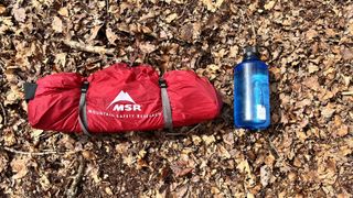 MSR Hubba NX tent packed in carry bag with water bottle for size comparison