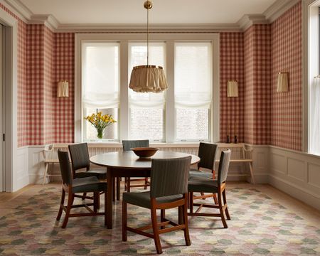 dining room with red gingham wallpaper and round wood table