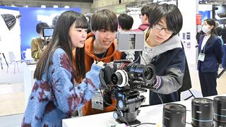 A photo from the 2024 CP+ show in Japan shows three visitors trying out a cinema camera