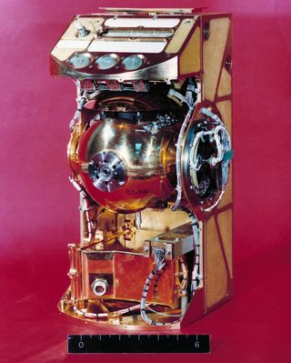 Traverse Gravimeter Experiment is a small golden box with a golden sphere exposed in the middle.