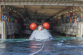 A mock Orion capsule in the well deck of a U.S. Navy amphibious transport ship.